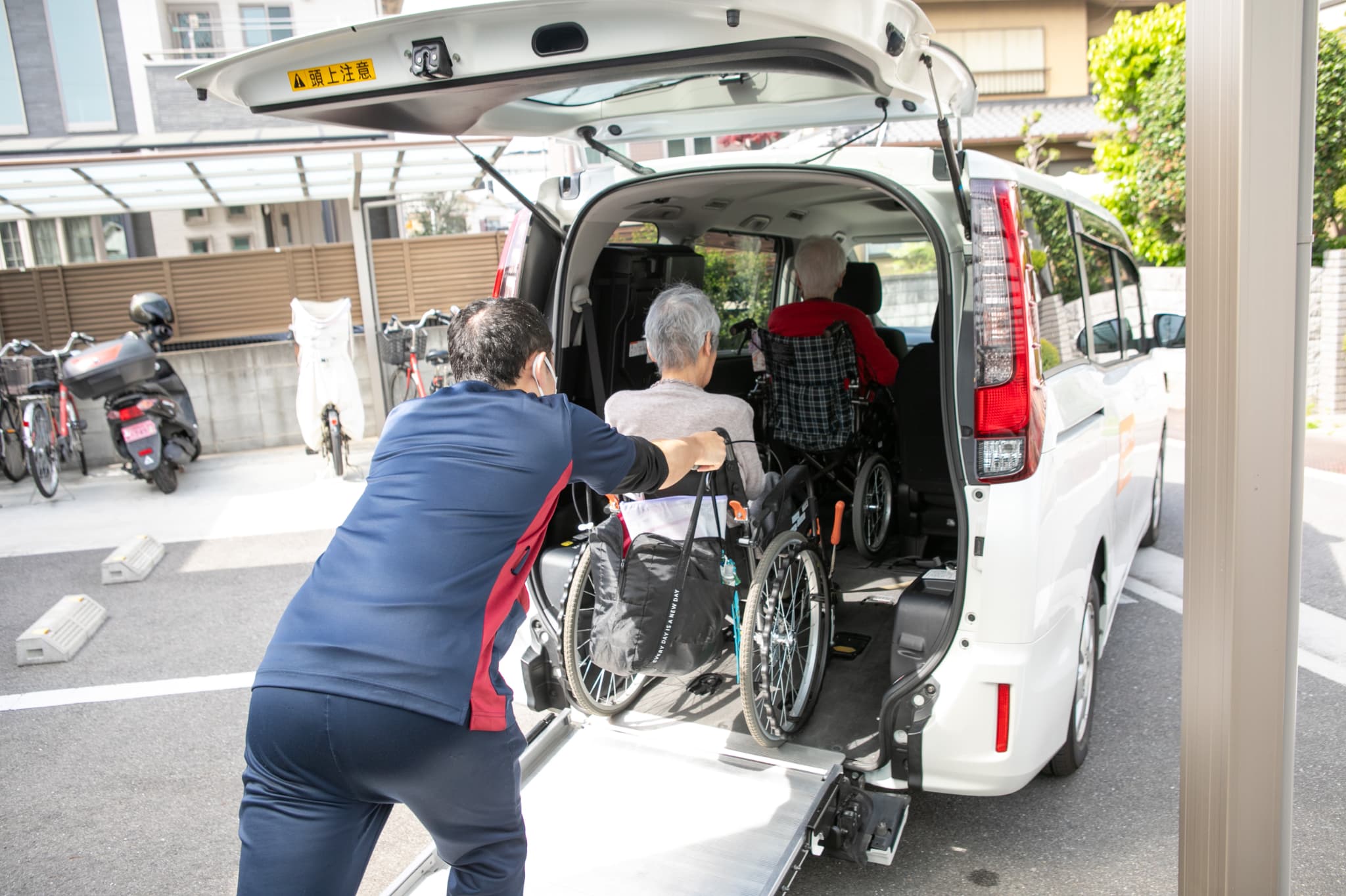 車いすの人を車に乗せるスタッフ