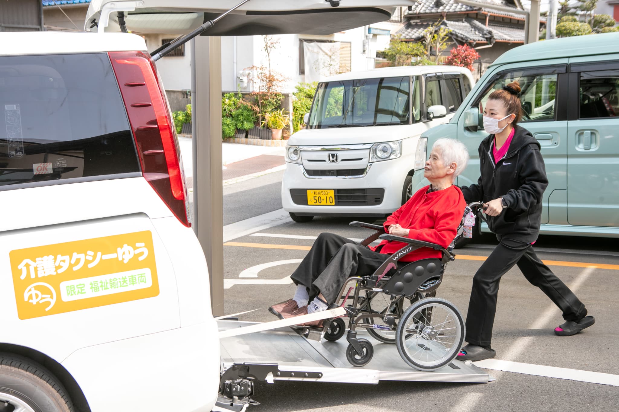 車いすの人を車に乗せるスタッフ