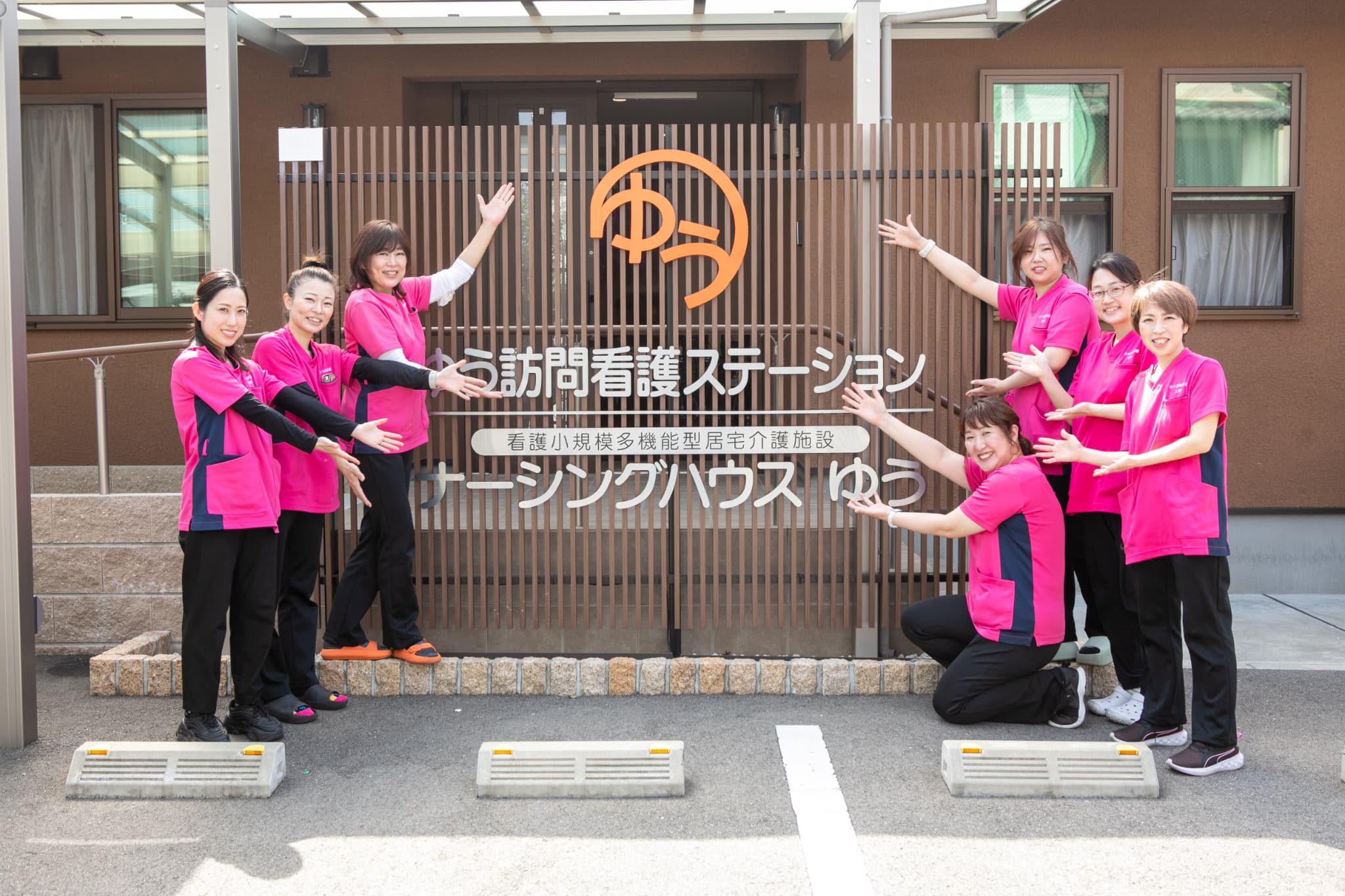 ゆう訪問介護ステーションの前でポーズを決めるスタッフ