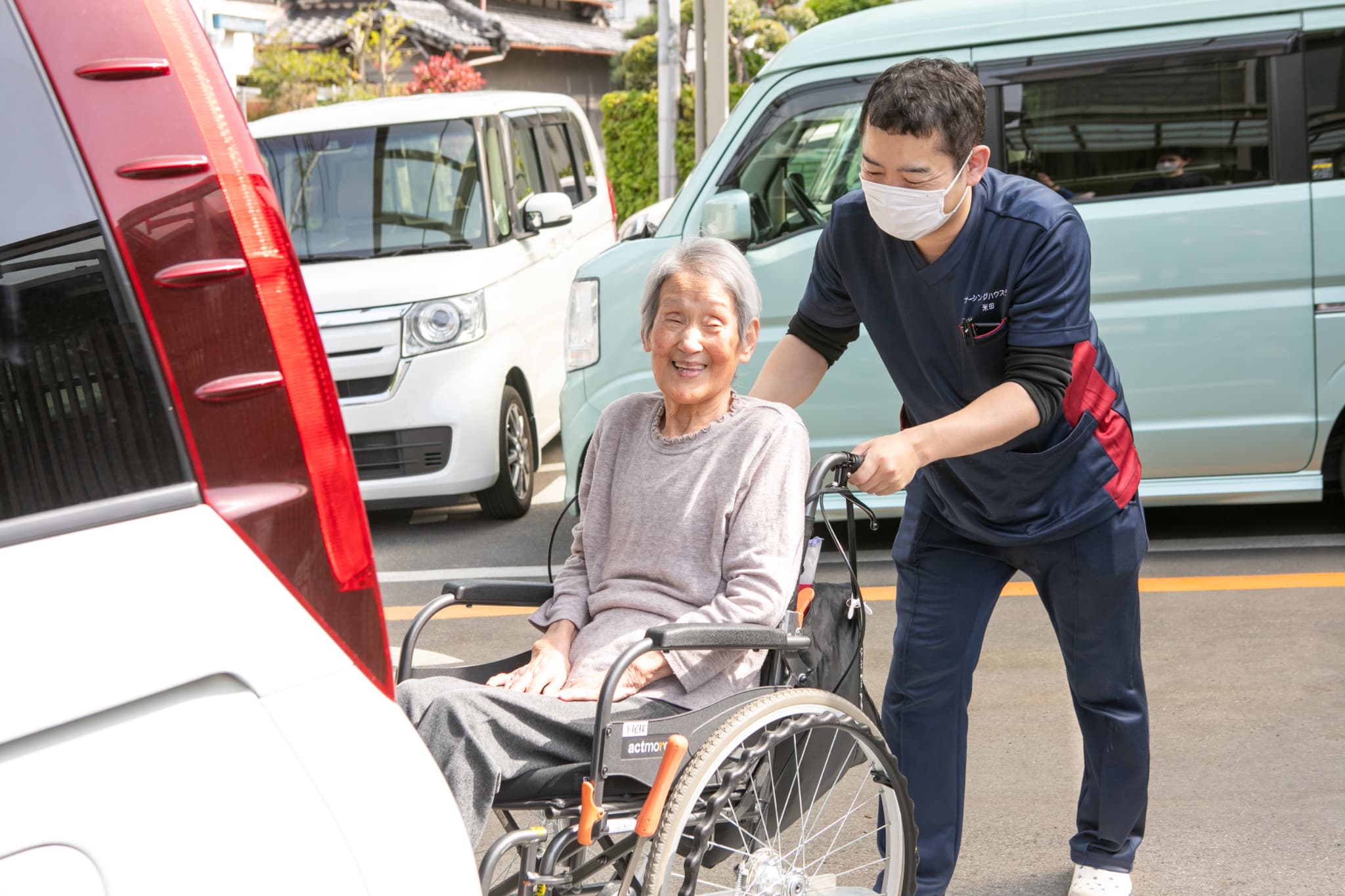 車いすの人を車に乗せるスタッフ