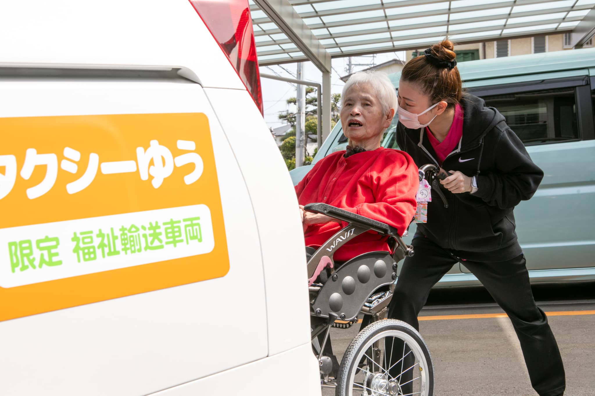 車いすの人を車に乗せるスタッフ